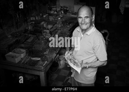 Homme photographié à l'entrée de son atelier où il fait de modèles de bateaux de Vittoriosa, Malte Banque D'Images