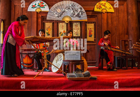 Trois femmes et un hommes jouer contre brown fond rouge. Banque D'Images