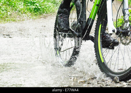 Mountain bike rider traverse un ruisseau Banque D'Images