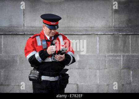 Un gardien de la circulation de billets de poche utilise une machine pour rendre une voiture en stationnement illégal à Cardiff au Pays de Galles. Banque D'Images