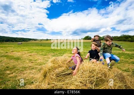 Les enfants courir et sauter dans un tas de paille, journée d'été Banque D'Images