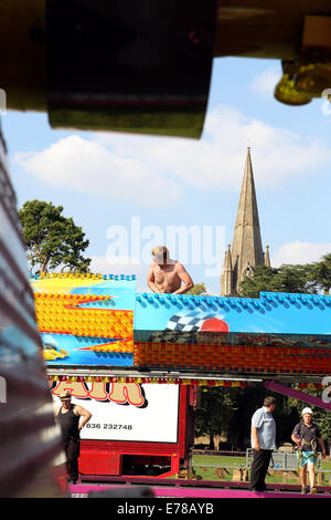 Witney, Oxfordshire, UK, le 9 septembre 2014. Les travailleurs forains créé un soleil de plomb en suspension dodgem en préparation de la fête à Witney ce weekend. La fête annuelle de St Mary a eu lieu depuis 1243 pour commémorer la nouvelle inauguration de l'église St Mary lorsque l'évêque a donné un cerf au Recteur afin que les gens de la ville ne pouvait célébrer l'occasion. Aujourd'hui un cochon rôti le vert de l'Église marque encore cette partie de la tradition aux côtés des manèges forains, sideshows, stands de nourriture, de la musique, et les événements sportifs Credit : Ric Mellis/Alamy Live News Banque D'Images