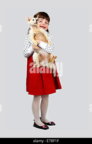 Petite fille avec des chat dans les mains. Portrait sur fond gris Banque D'Images