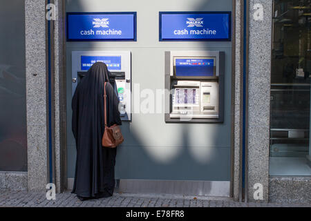 Une femme dans une burqa à l'aide d'une machine à cash d'Halifax Banque D'Images