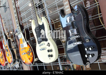 Groupe de guitares électriques brillant accroché sur un mur et à la vente. Photographié sur un angle. Banque D'Images