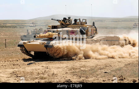 Une armée américaine M1A2 Abrams char de combat principal affecté à la Garde nationale du Minnesota races à travers une brèche dans les barbelés d'un obstacle lors de la 116e d'entraînement au combat eXportable de l'exercice dans le centre de formation de combat Orchard, Maryland, le 21 août, 2014. L'scalab Banque D'Images