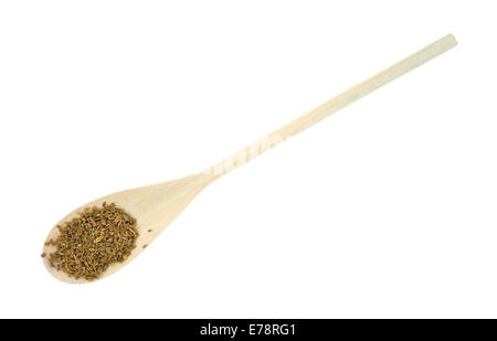 Une longue cuillère en bois avec des graines sur un fond blanc. Banque D'Images