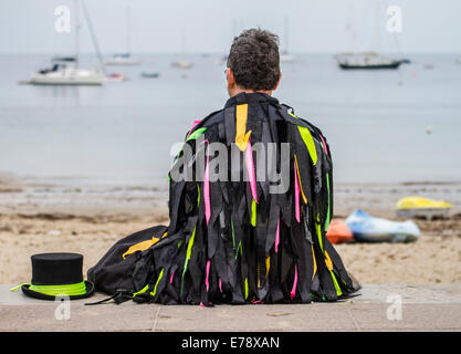 Danseur traditionnel morris assis sur marche à côté dans la baie avec des yachts avec chapeau à ses côtés Banque D'Images