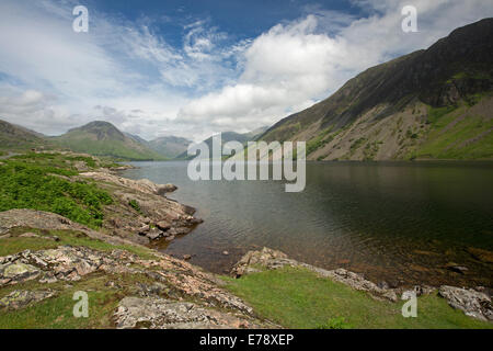 Lac Wastwater entourée de sommets de montagnes recouvertes de végétation verte, ciel bleu avec des nuages bas, Lake District, Cumbria England Banque D'Images