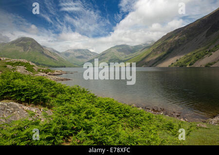 Lac Wastwater entourée de sommets de montagnes recouvertes de végétation verte, ciel bleu avec des nuages bas, Lake District, Cumbria England Banque D'Images