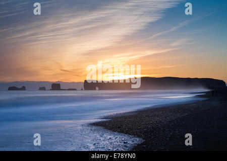 La vue le long de la plage de sable noir de Reynisfjara qui jouit près du village de Vík í Mýrdal vers Dyrhólaey au crépuscule, le sud de l'Islande Banque D'Images