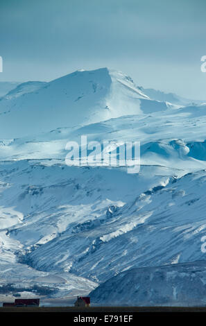 Farmhouses éclipsées par la masse de glace, le sud de l'Islande Eyjafjallajökull Banque D'Images