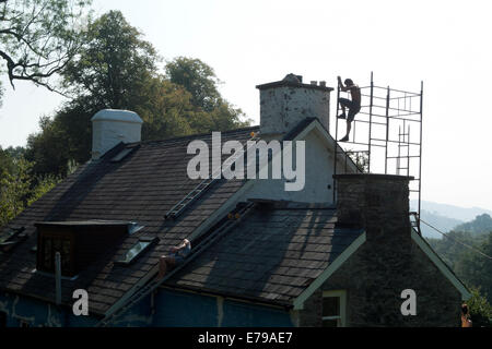 Silhouette de l'homme qui monte sur un échafaudage en cours de réparation Une cheminée sur une maison dans la campagne rurale gallois Carmarthenshire pays de Galles Royaume-Uni KATHY DEWITT Banque D'Images