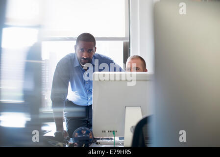 Deux hommes travaillant dans un bureau, à la fois à l'écran d'un ordinateur. Banque D'Images