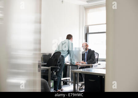 La vie de bureau. Deux personnes parlent de plus d'un bureau. Banque D'Images