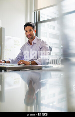 La vie de bureau. Un homme assis à son bureau. Banque D'Images