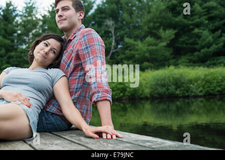 Un couple de détente sur une jetée donnant sur un lac de montagne. Banque D'Images