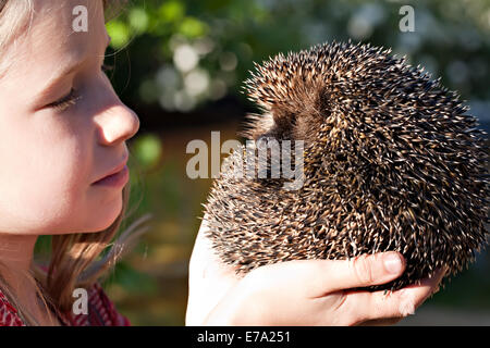 Little smiling girl avec mignon hérisson européen balle en mains, deux Vue de profil Banque D'Images