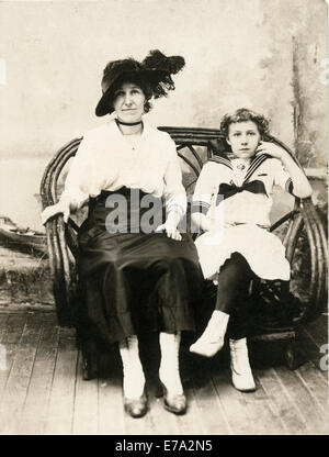 Woman in Black Hat with Teenage Girl en tenue de marin assis sur la chaise en rotin, Portrait, vers 1910 Banque D'Images