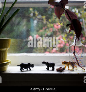 Une ligne de jouets en plastique miniature animaux sur un rebord de fenêtre Banque D'Images