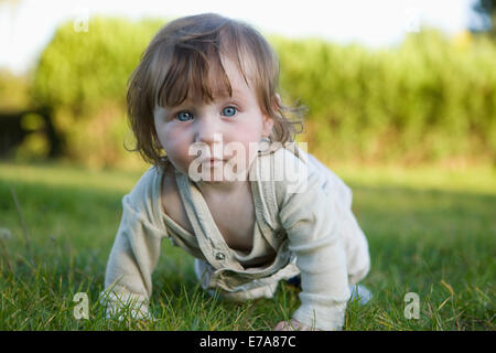 Baby Girl ramper dans l'herbe, looking at camera Banque D'Images