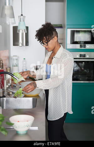 Jeune femme laver les légumes dans la cuisine Banque D'Images