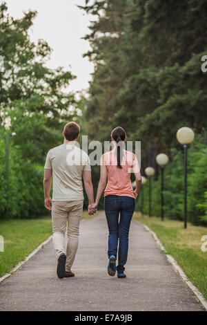 Vue arrière du jeune couple en train de marcher tout en tenant les mains dans park Banque D'Images