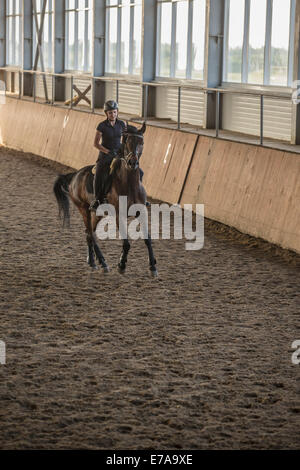 Toute la longueur du cheval équitation femme en training stable Banque D'Images