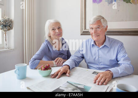 Portrait of happy senior couple sitting avec table à journaux Banque D'Images