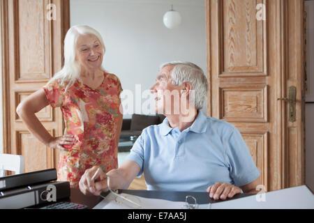 Man looking at woman alors que le calcul accueil finances at table Banque D'Images