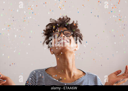 Happy young woman de confettis tombant sur son sur fond gris Banque D'Images