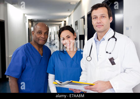 Deux médecins dans scrubs et un médecin dans un manteau de laboratoire dans un couloir de l'hôpital Banque D'Images