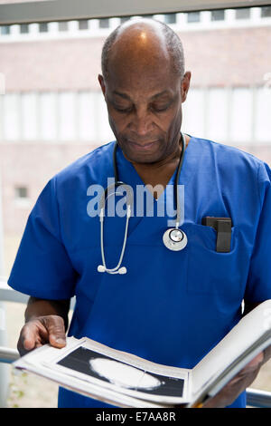 Portrait d'un médecin dans scrubs l'examen d'un dossier médical Banque D'Images