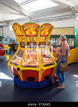 La femme et son enfant jouer sur une machine à sous appelée Rhythm and Blues sur la jetée de Teignmouth, dans le Devon (Angleterre). Banque D'Images