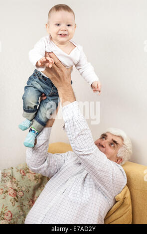 Heureux grand-père petit-fils holding while sitting on sofa Banque D'Images