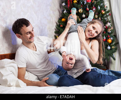 Jeune famille avec un bébé de s'amuser sur le lit chez lui Banque D'Images