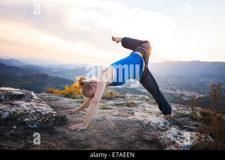 Young Caucasian woman performing yoga pose chien tête en bas à l'extérieur Banque D'Images