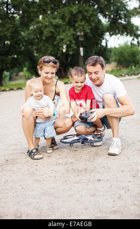 Jeune famille avec deux garçons jouant avec rc jouet quadrocopter Banque D'Images