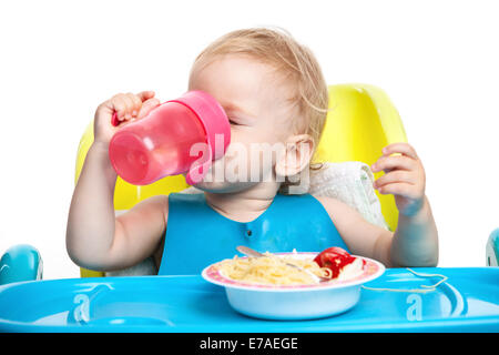 L'eau potable et de petit garçon assis à table avec assiette de spaghetti Banque D'Images