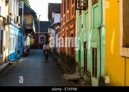 Une petite ruelle aux maisons colorées et un cycliste, Panaji, Goa, Inde Banque D'Images