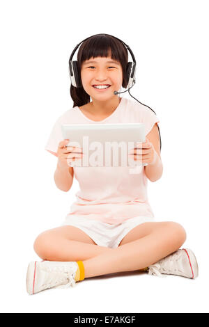 Assis little girl holding a tablet avec écouteurs.isolé sur fond blanc Banque D'Images