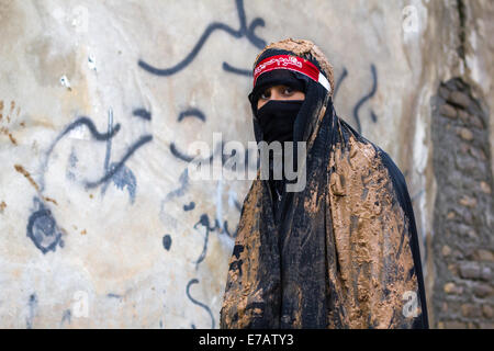 Jeune femme musulmane chiite, vêtu d'un tchador noir couvert de boue, de deuil pendant le jour de l'Achoura dans Bijar, Iran. Banque D'Images