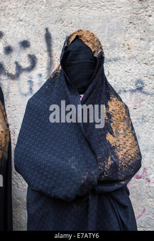 Une femme musulmane chiite, vêtu d'un tchador noir couvert de boue, de deuil pendant le jour de l'Achoura dans Bijar, Iran. Banque D'Images