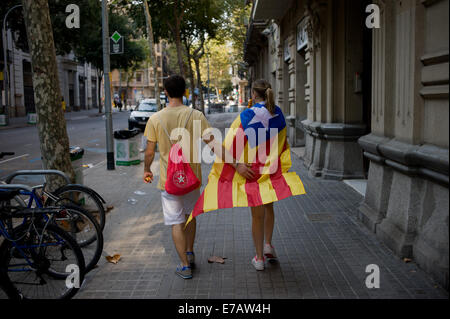 Barcelone, Espagne. Sep 11, 2014. Un couple portant un drapeau catalan indépendantiste promenades dans les rues de Barcelone. Une grande manifestation en faveur de l'indépendance a eu lieu dans les rues de Barcelone pendant la fête nationale catalane exigeant la célébration d'un referundum d'une sécession de l'Espagne le 9 novembre prochain. Crédit : Jordi Boixareu/Alamy Live News Banque D'Images