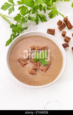 Soupe de pain avec des croûtons et des herbes sur la table en bois blanc, vue du dessus Banque D'Images