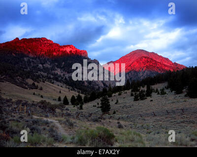 De hautes montagnes avec coucher du soleil rougeoyant dans la lumière rouge du soir Banque D'Images