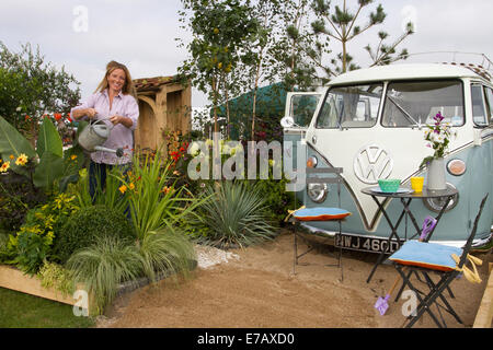 1966 VW Volkswagen transporteur VeeDub splitty, hippie van, campervan Type 2, 60s kombi, camping-car combi à Harrogate, Yorkshire, Royaume-Uni. 11 septembre 2014. Samantha Guthrie, arrosant les plantes au salon floral annuel d'automne de Harrogate, Yorkshire Showground, avec le jardin NSPCC "A Journey Through Childhood", qui a remporté un Gold Award et inclus, après une restauration complète Roxy, les campeurs VW T2 à écran divisé, ou campervan 1966 refroidis par air. Camping-cars Splitscreen, kombi ou combi. Banque D'Images