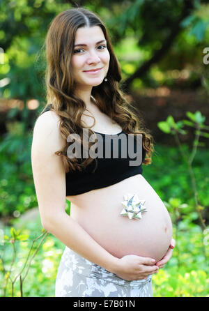 Une enceinte de 9 mois pose modèle dans la nature avec un arc sur son ventre. Banque D'Images