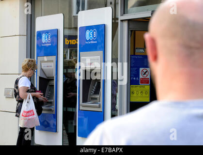 L'homme à la tête rasée regardant femme plus âgée à l'aide d'un distributeur de billets Banque D'Images