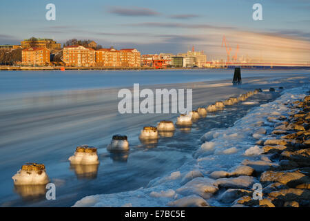 L'eau glacée sur le bord d'une rivière qui coule par une ville Banque D'Images